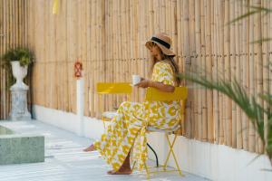 a woman sitting in a chair with a cup of coffee at Lime Splash Private pool in Choeng Mon Beach