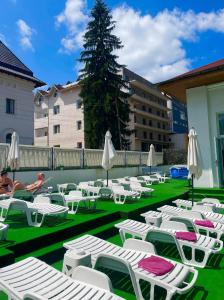 a group of lounge chairs and umbrellas on a lawn at Hotel Olanesti & Spa Medical in Băile Olăneşti