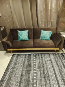 a brown couch with two blue pillows on a rug at DREAM Room , AJMAN in Ajman 