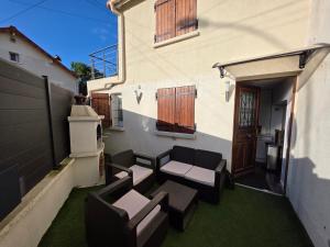 a patio with a couch and chairs on the side of a house at Maison de ville entièrement équipée in Argenteuil +7 photos