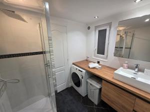 a bathroom with a washing machine and a sink at Maison de ville entièrement équipée in Argenteuil
