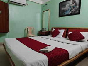 a bedroom with a large bed with red and white pillows at Oasis Hotel and Restaurant in Siliguri