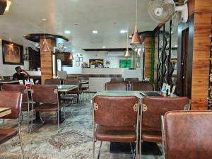 a dining room with tables and chairs in a restaurant at Oasis Hotel and Restaurant in Siliguri