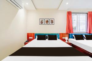 two beds in a room with red curtains at Hotel O Mahakal Temple Formerly Shivangam in Ujjain