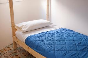 a bed with a blue comforter and a white pillow at Bed in Girona in Girona