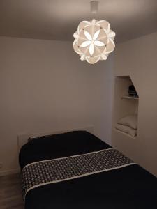 a bedroom with a black bed and a chandelier at L'Ancienne Etable in Gentelles