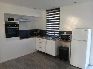 a kitchen with white cabinets and a white refrigerator at L'Ancienne Etable in Gentelles