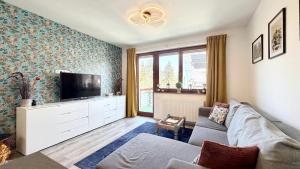 a living room with a couch and a flat screen tv at Aurora Apartman in Kőszeg