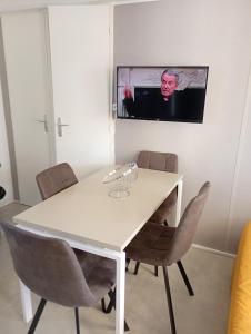 a white dining room table with chairs and a tv on the wall at Mobile-Home L'Instant Marin in Sérignan