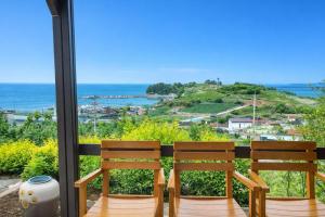 two chairs sitting on a balcony looking out at the ocean at Orchard 123 Private Pension in Yeosu