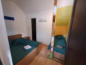 a small bedroom with a green bed and a mirror at Casa Bunicii in Podu Dîmboviţei