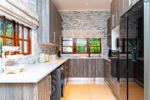 a kitchen with wooden cabinets and a stone wall at Hoyozela in Hartbeespoort