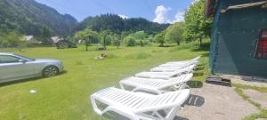 a row of white lounge chairs in a field at Casa Bunicii in Podu Dîmboviţei