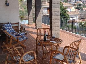 a patio with a table and chairs and a bottle of wine at At Armando's Home in Zafferana Etnea