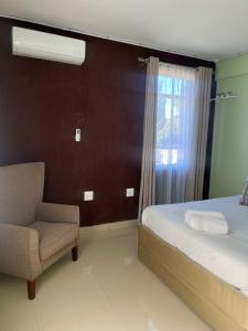 a bedroom with a bed and a chair and a window at 112 On Park Drive in Gqeberha +2 photos