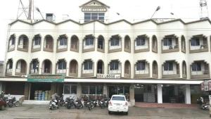 a white building with motorcycles parked in front of it at Kdk lodge in Pollāchi