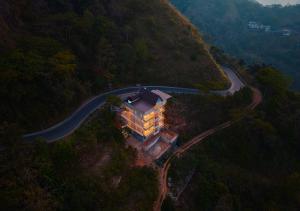 a building on the side of a hill with a road at Hill Breeze Pool Resort Vagamon by VOYE HOMES in Vagamon