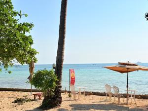 a beach with chairs and an umbrella and the ocean at Samma Karuna Beach & Wellness Resort - Intoxicants free in Srithanu