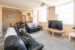 a living room with a leather couch and a flat screen tv at Hill House Apartment in Framlingham