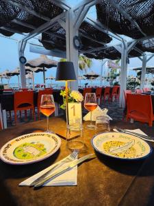 a table with two plates and wine glasses on it at Beach Club Ippocampo in Ippocampo