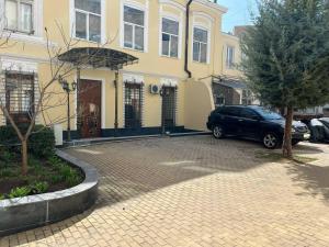 Ein Auto parkte vor einem gelben Gebäude in der Unterkunft De Versal in Odessa