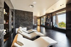a living room with white chairs and a wall of black tiles at Hotel Riviera & Maximilian's in Trieste