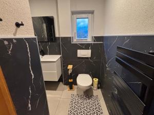 a black and white bathroom with a toilet and a window at Ferienwohnung Grünblick am Katschbach in Teufenbach