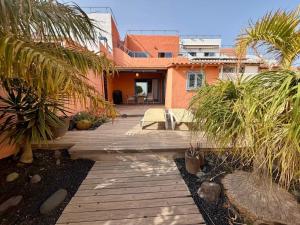 a wooden walkway in front of a house with palm trees at Montaña Blanca - Casa Bimba in Caleta De Fuste