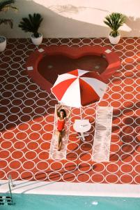 a toy of a person sitting under an umbrella next to a swimming pool at Romeos Ibiza - Adults Only in San Antonio Bay