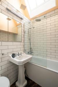 a white bathroom with a sink and a bath tub at Hill House Apartment in Framlingham +24 photos