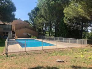 a fence around a swimming pool in front of a house at Cozy Duplex in Arles