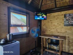 a room with a desk and a fan and a television at Oluhle Resort in Hammanskraal