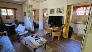 a living room with a large television and a table at Alpaca Self Catering Cottage Kleinmond in Kleinmond