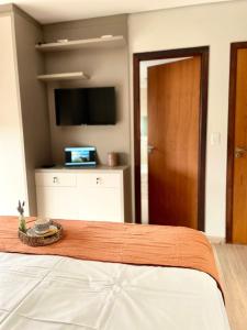 a bedroom with a bed with a flat screen tv at Villa Serena Garden - Suíte com Hidromassagem - Ideal Casal in Cascavel