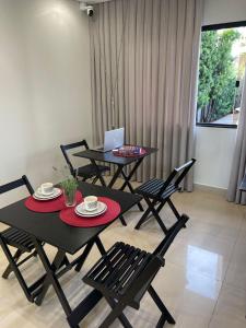 a dining room with two tables and chairs and a laptop at Villa Serena Garden - Suíte com Hidromassagem - Ideal Casal in Cascavel
