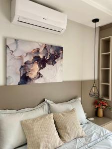 a bedroom with a bed with a painting on the wall at Villa Serena Garden - Suíte com Hidromassagem - Ideal Casal in Cascavel