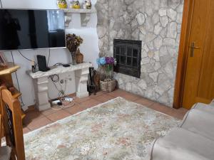 a living room with a stone fireplace and a television at Casa do Limoeiro - Casa in Golegã