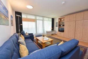 a living room with a blue couch and a table at Haus "Panorama" Appartement PAN019 in Duhnen