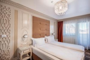 a bedroom with a large white bed and a chandelier at Grădina Mariajelor Hotel in Câmpulung Moldovenesc