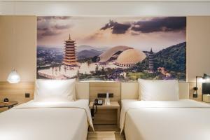 two beds in a hotel room with a painting on the wall at Atour Hotel Maqun Nanjing in Nanjing