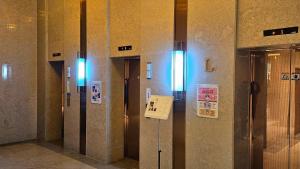 a row of elevators in a building with signs on the wall at SainTree Hotel in Incheon