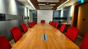 a conference room with a long table and red chairs at SainTree Hotel in Incheon