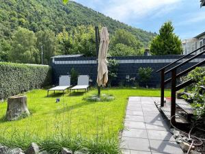a patio with two chairs and an umbrella in the grass at Ferienhaus Elda in Lahnstein