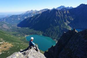 a person sitting on top of a mountain overlooking a lake at Tatra Góral Ski Apartament in Murzasichle +54 photos
