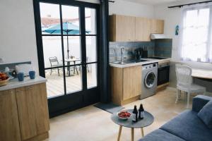 a kitchen with a couch and a table in a room at Residence Clos des Aigrettes -Appartements a 30m du Port de La Cotiniere , Ile d Oleron -commerces et plages a pied in La Cotinière
