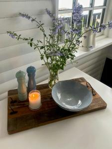 a candle and a plate on a cutting board with flowers at Breathtaking Sea View At Dinestrup Beach in Ullerslev +32 photos