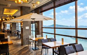 a restaurant with tables and chairs and a large window at SainTree Hotel in Incheon