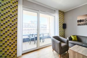 a living room with a couch and a table with a balcony at ADAPT APARTMENT HOTEL Wetzlar in Wetzlar