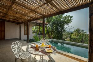 a patio with a table and chairs and a pool at SaffronStays Rustic Trails in Mulshi