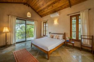 a bedroom with a large bed in a room with windows at SaffronStays Rustic Trails in Mulshi +43 photos